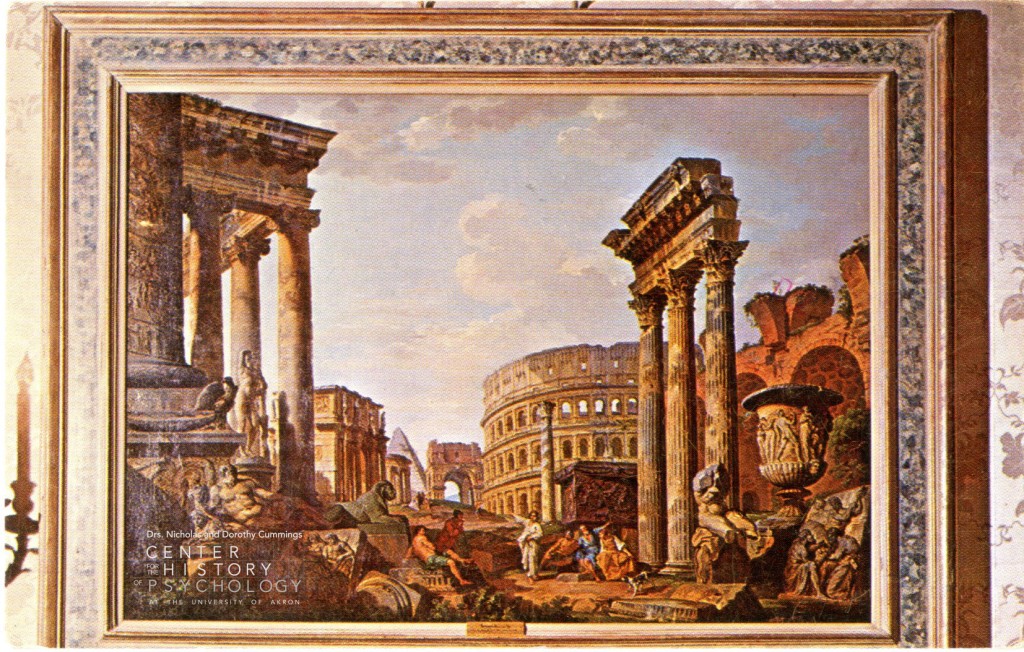 A postcard view of a framed painting depicting Roman ruins. The Colosseum is visible in the background of the image and pillars from the Roman Forum are in the foreground. A group of six people in robes appear to be lounging at the base of the pillars. Logo of the Center for the History of Psychology appears in the bottom left corner. 