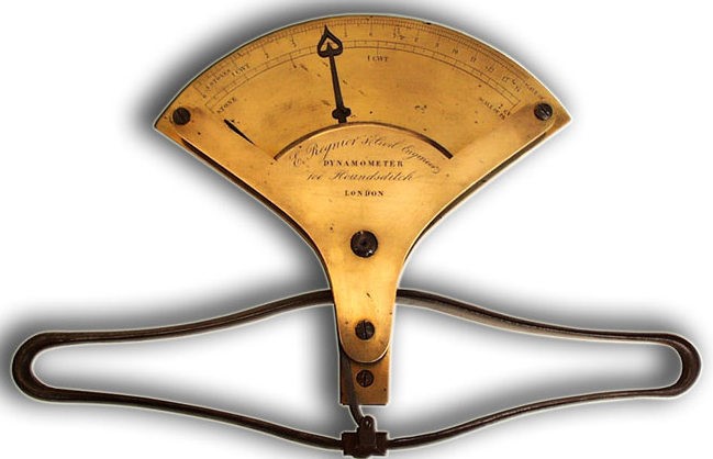 A brass plate with numerical markings and a moveable hand. At its base, there is a rounded metal bar, designed to be gripped by two hands.